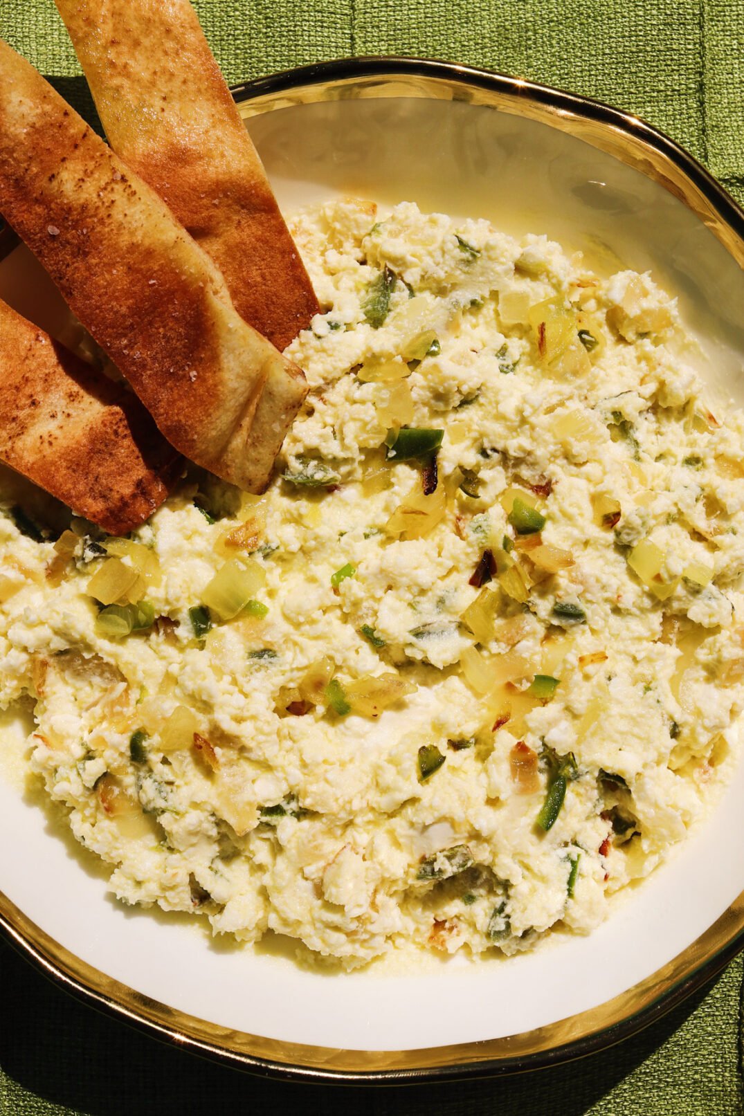 Cava's crazy feta recipe in a white bowl with pita chips and a green background. 
