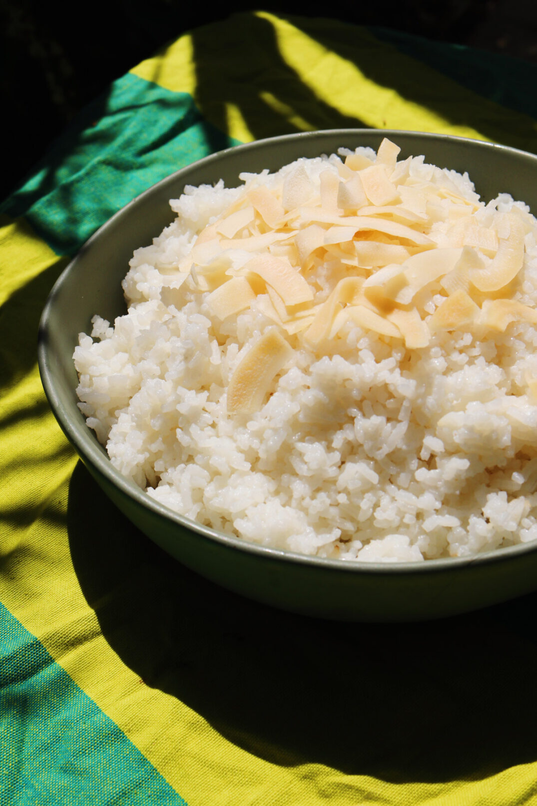 the side view of a green bowl filled with coconut rice cooked in a rice cooker. 