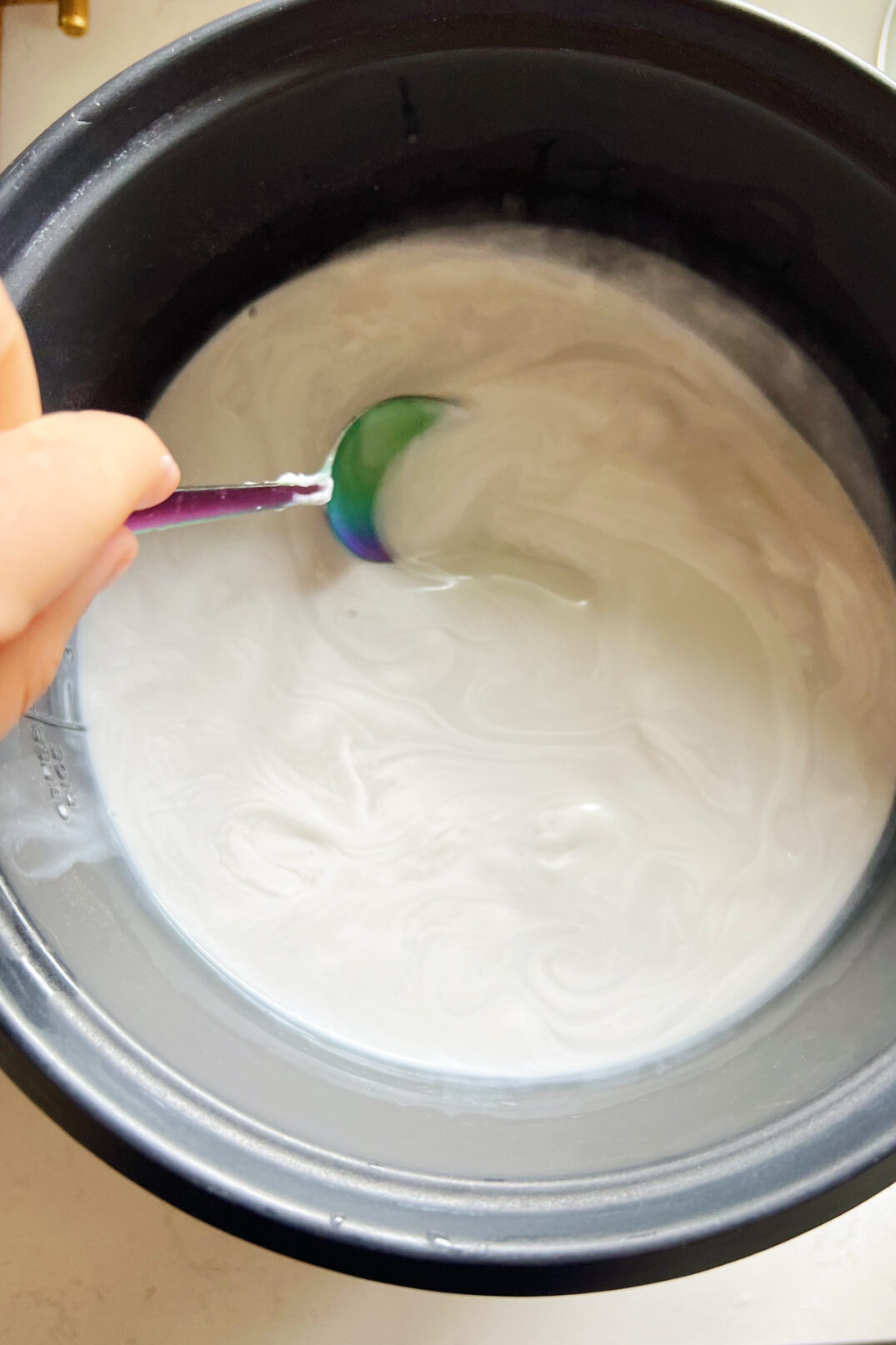 stirring heated coconut milk into water in a rice cooker. 