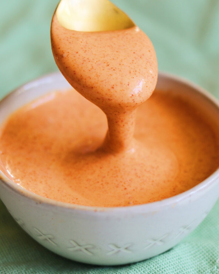 a small white bowl filled with creamy sriracha sauce.