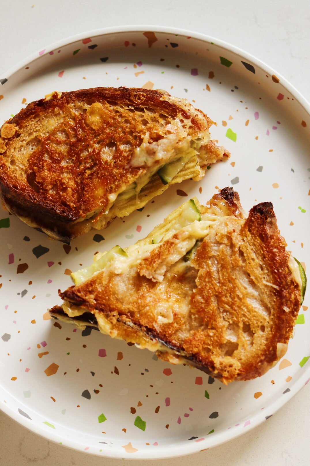 two halves of a grilled cheese with dill havarti, dill pickles and dill potato chips.