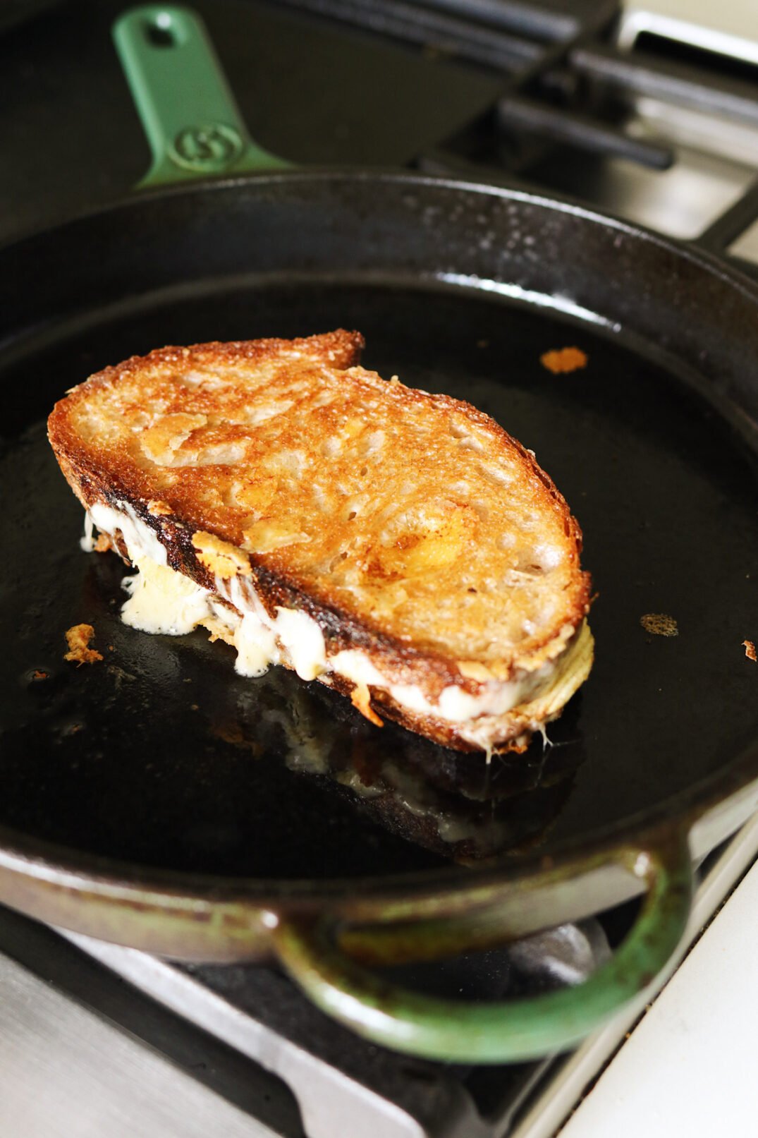 a grilled cheese being cooked in a cast iron skillet.