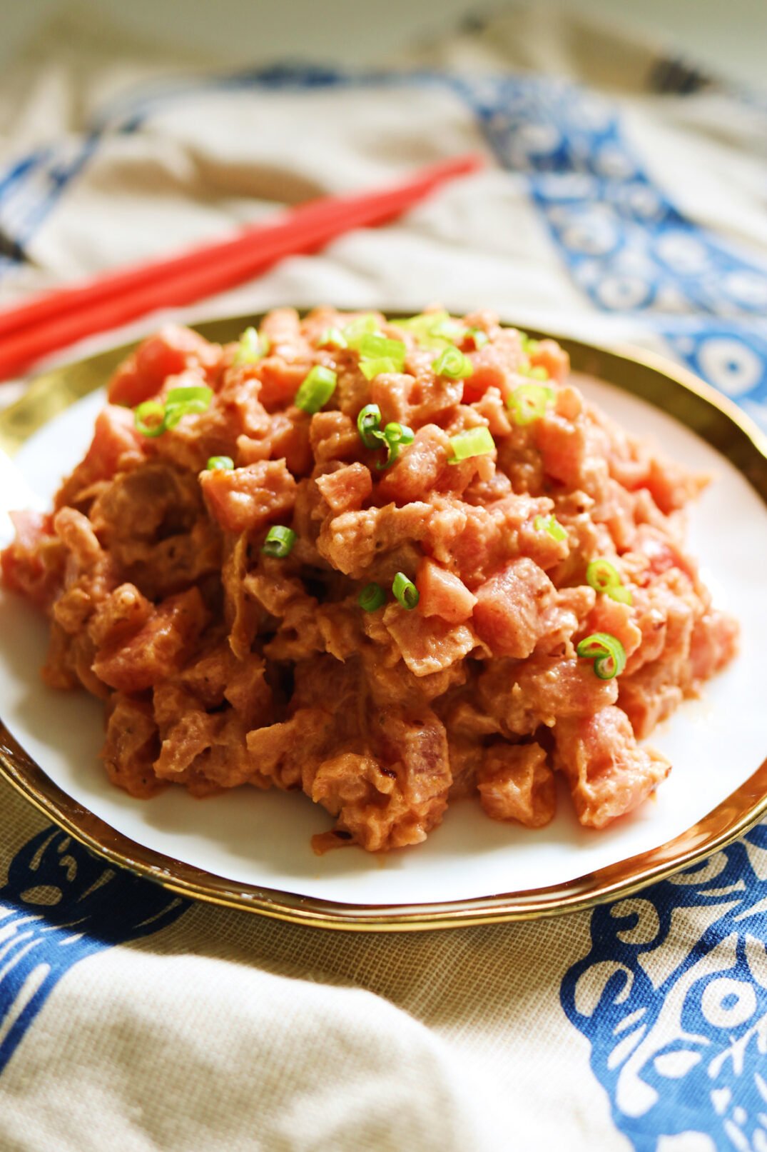 a plate of spicy tuna mixture with red chopsticks in the background. 