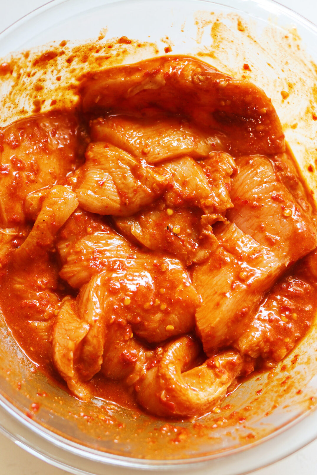 chunks of harissa marinated chicken in a glass bowl. 
