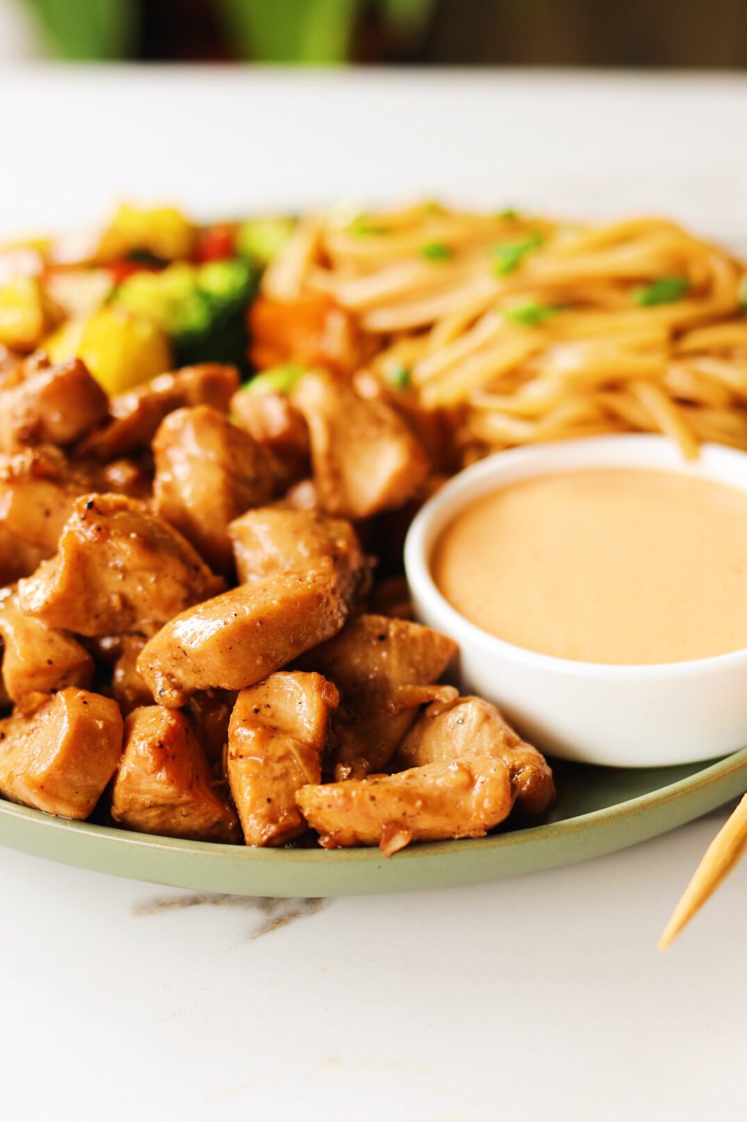 a plate of hibachi chicken with yum yum sauce on a green plate with chopsticks.