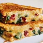 two halves of a marry me grilled cheese oozing cheese out sitting on a plate.