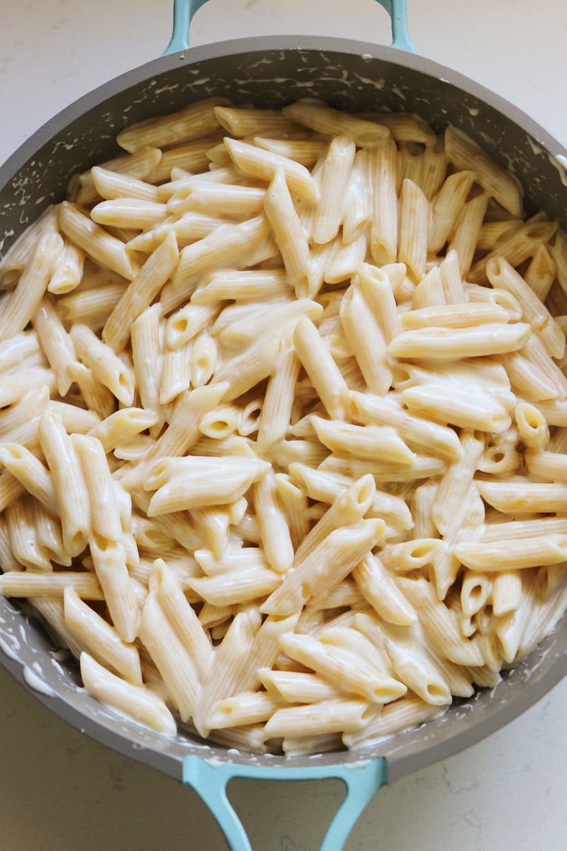 an overhead view of a blue our place pan filled with penne alfredo. 