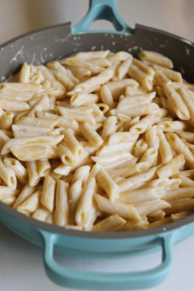 a big blue our place pan filled with creamy penne pasta. 