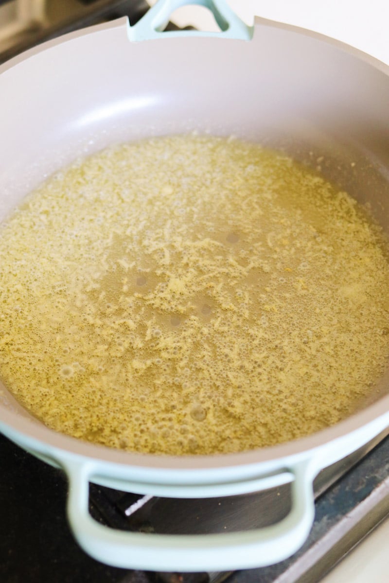 garlic and butter being melted in a blue pan. 