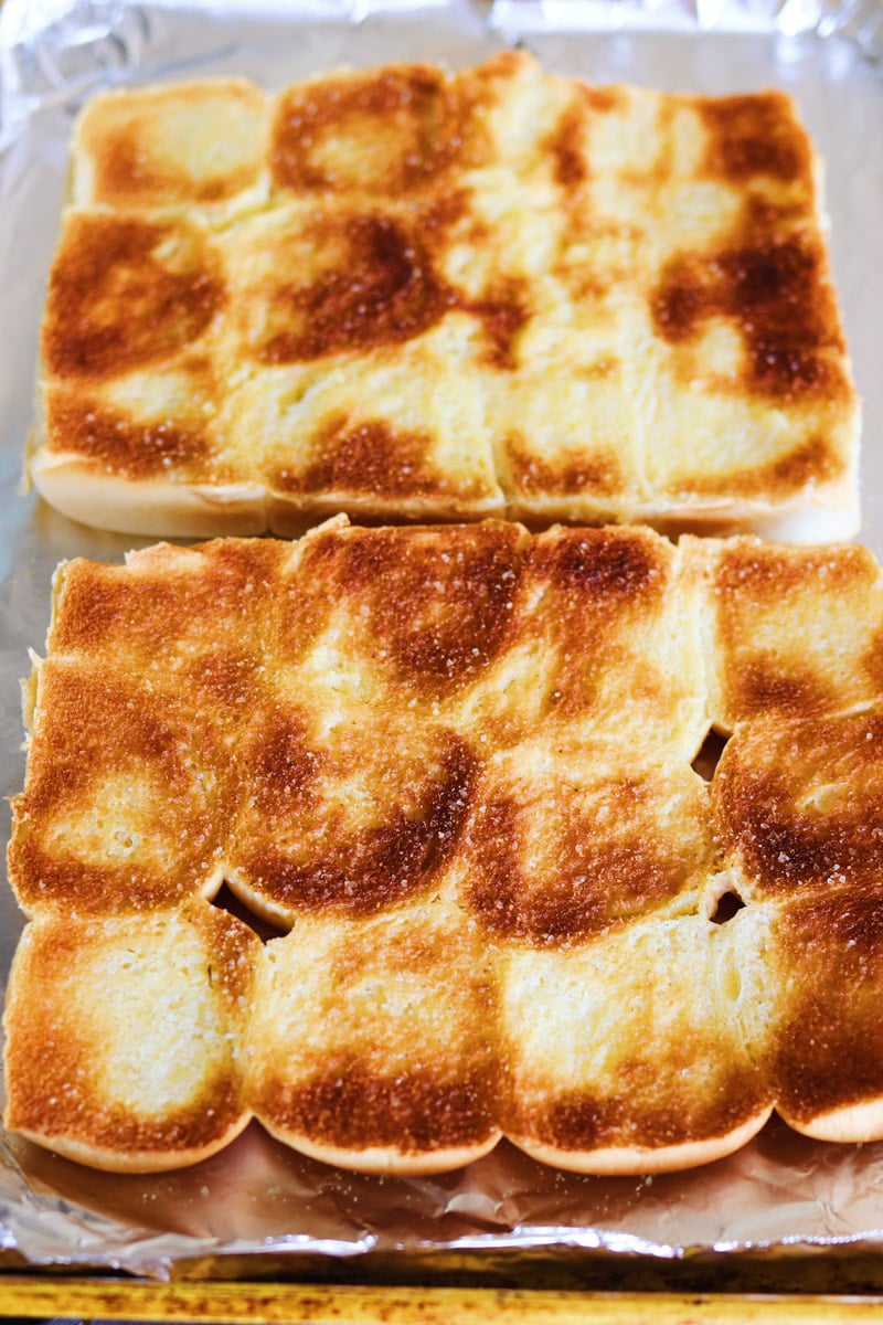 toasted hawaiian bread garlic bread on a tinfoil lined baking sheet.