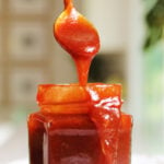a small jar of southern bbq sauce recipe with a golden spoon pouring it.