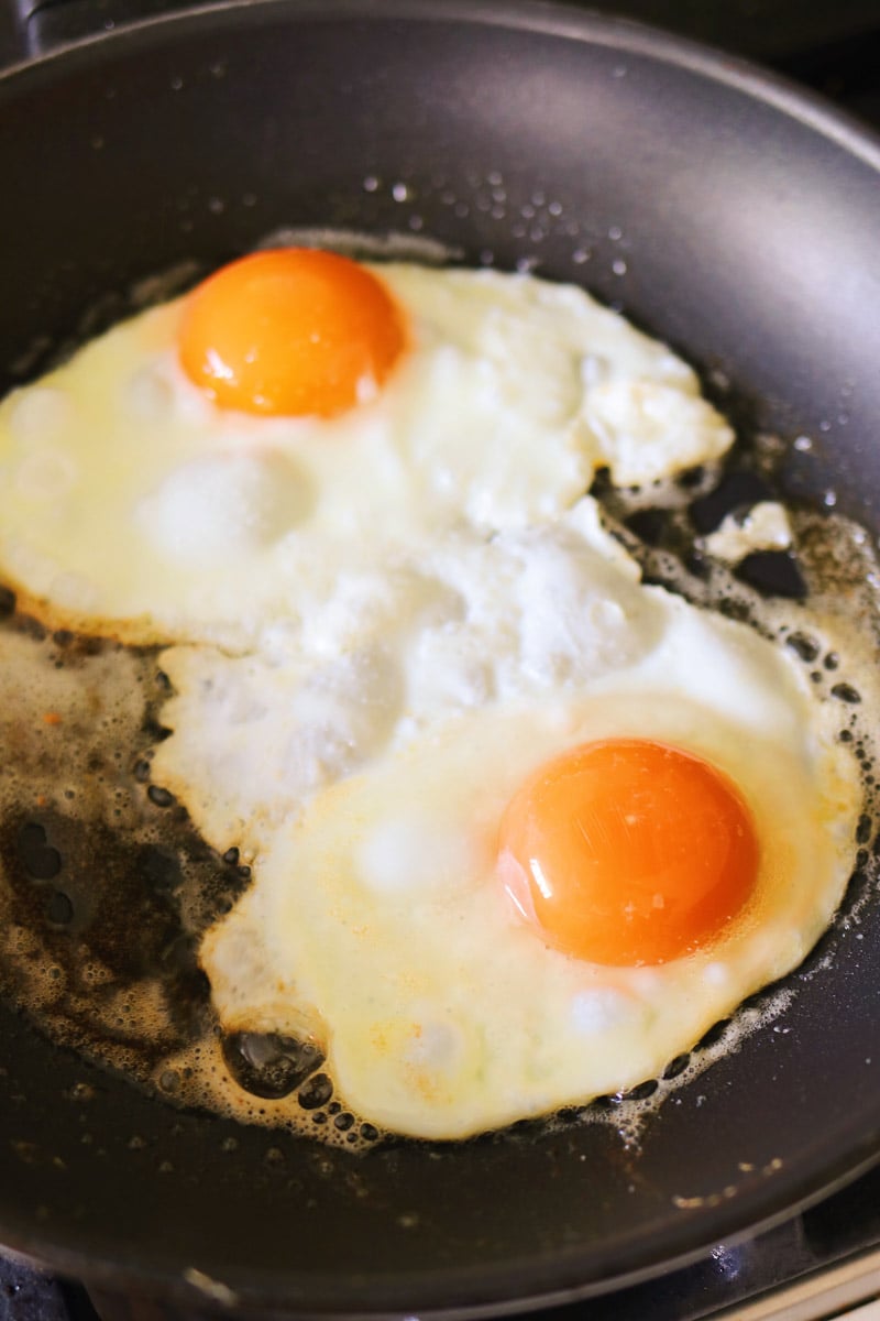 two eggs frying in a nonstick skillet