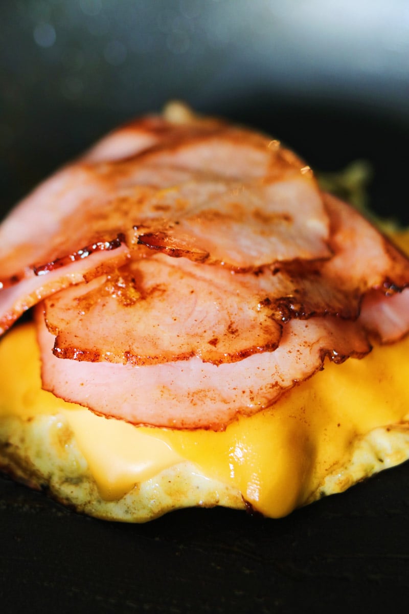 a stack of ham, egg and melted cheese in a nonstick skillet. 