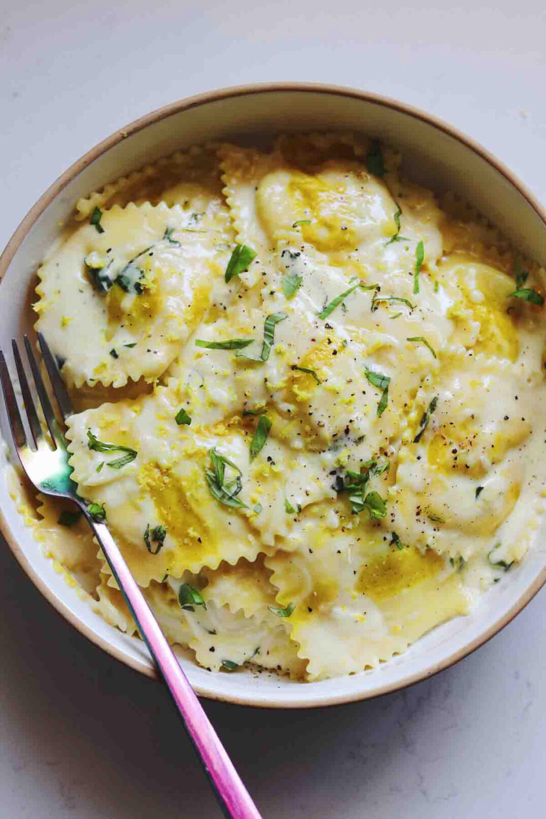 a white bowl full of trader joes sweet corn ravioli with lemon butter cream sauce