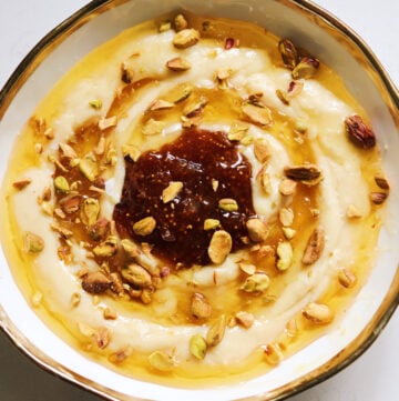 a white bowl with a golden rim topped with whipped brie, honey and fig jam.