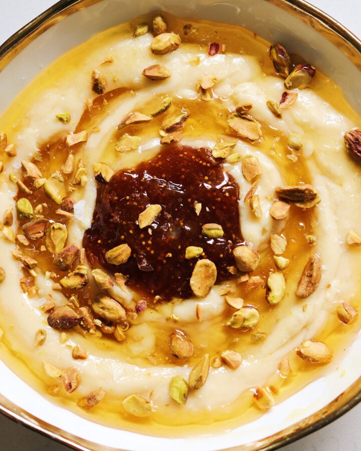 a white bowl with a golden rim topped with whipped brie, honey and fig jam.