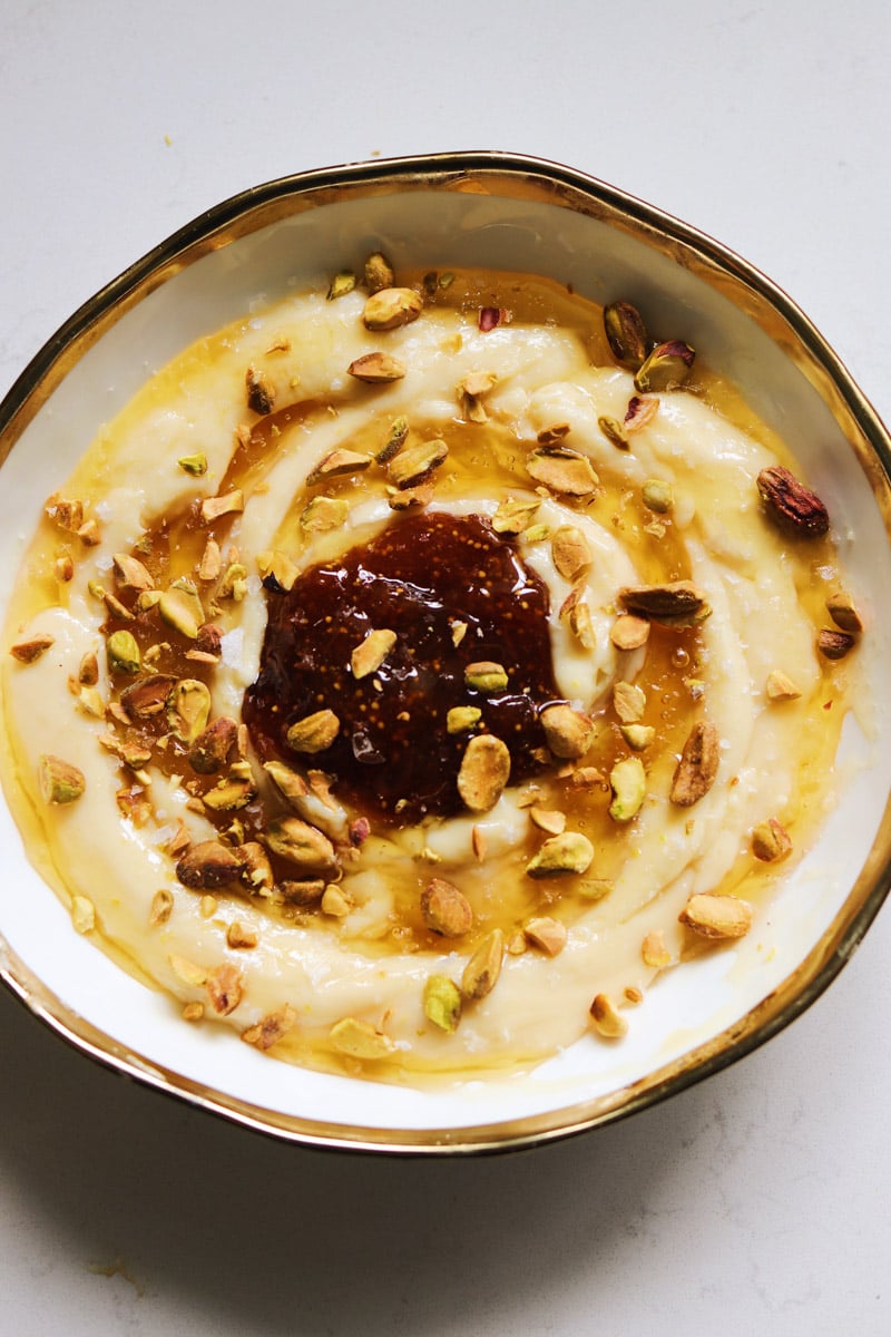 A white bowl with a golden rim filled with whipped brie, fig jam and honey.