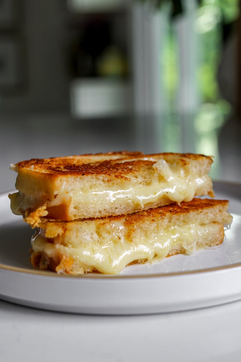 two halves of a garlic bread grilled cheese made with toum on a white plate. 