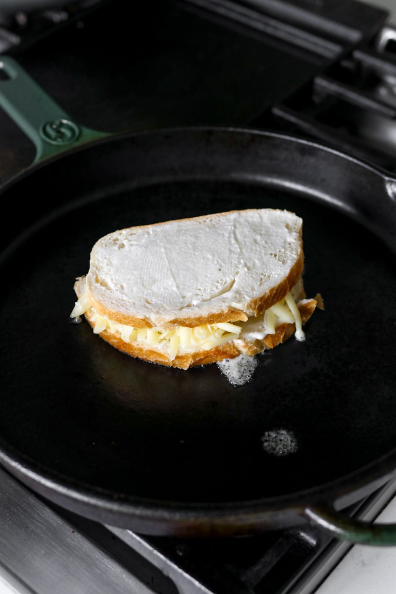 a garlic bread grilled cheese cooking in a large cast iron skillet.