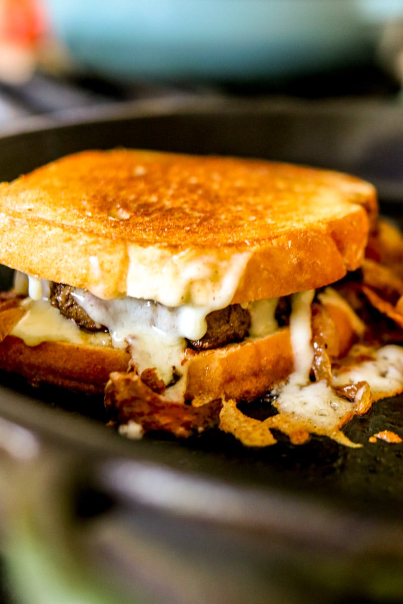 a bubba burger patty melt on a frying pan cooking. 