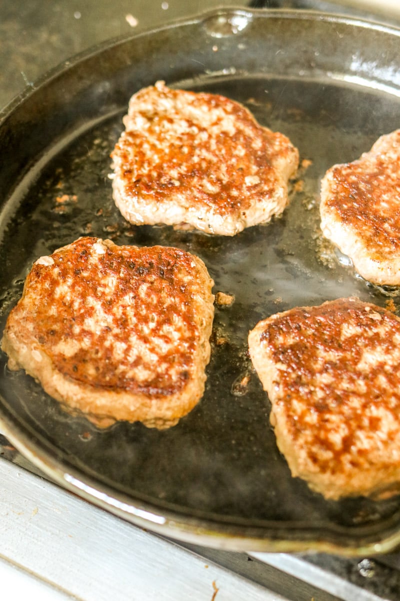 bubba burgers being fried in a large cast iron skillet. 
