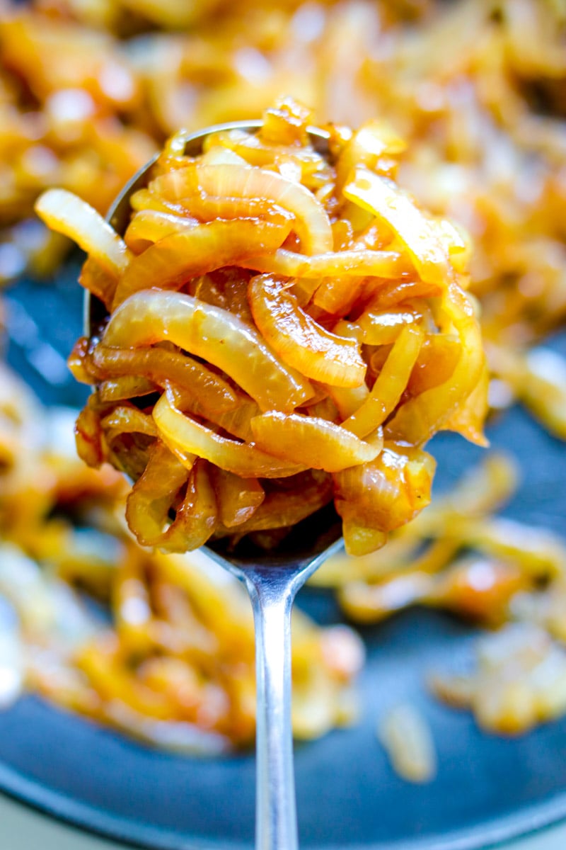 a spoon holding a scoop of quick caramelized onions. 