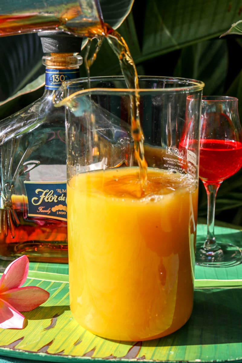 pouring rum into a pitcher of rum punch. 