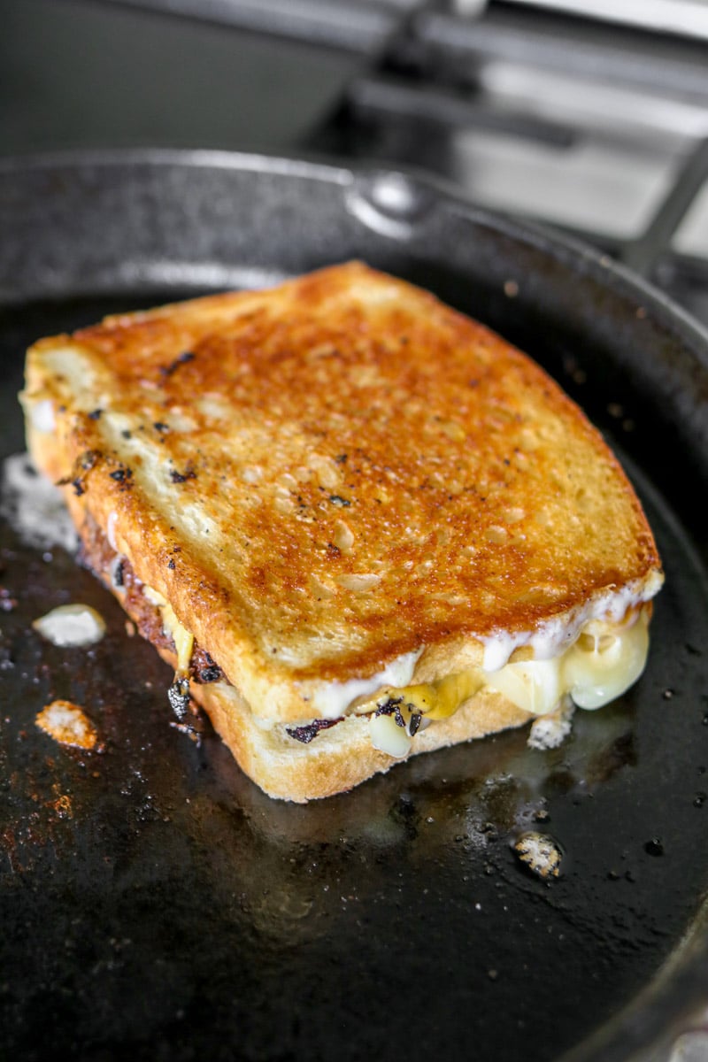 a burger grilled cheese cooking in a frying pan.