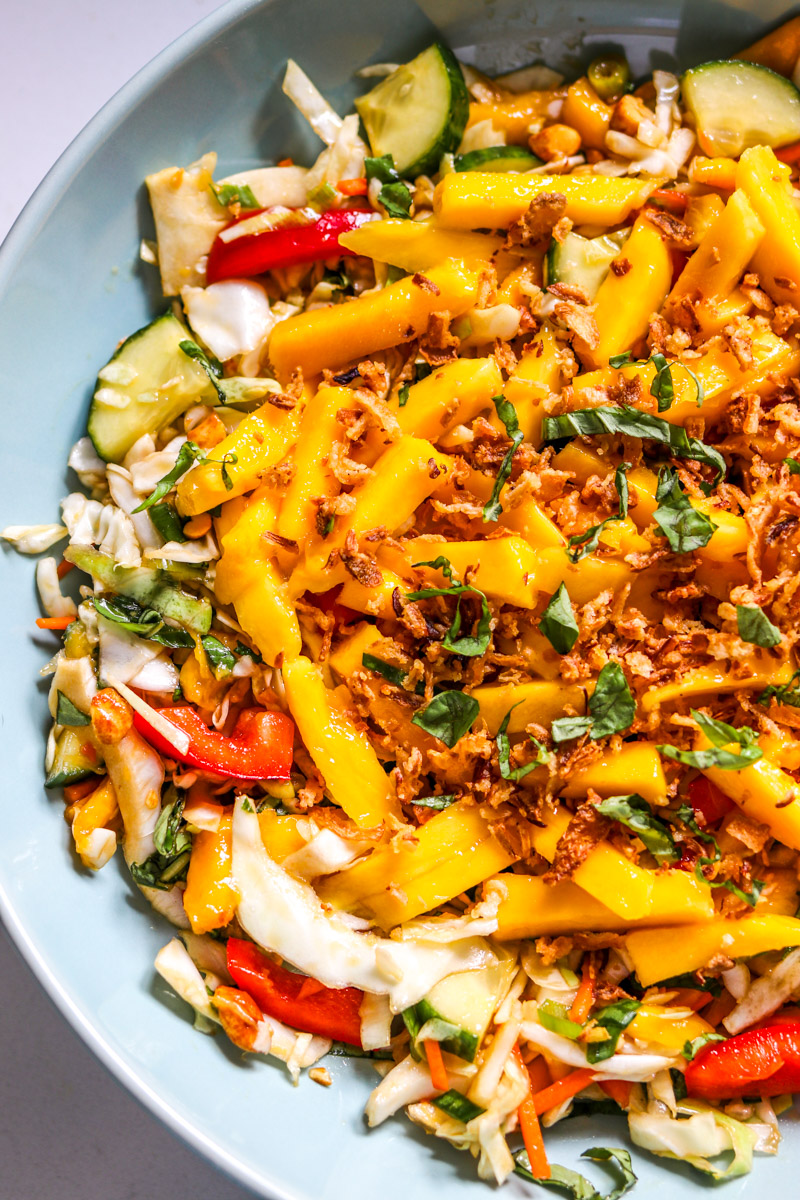 the right side of a bowl filled with colorful thai inspired mango salad.