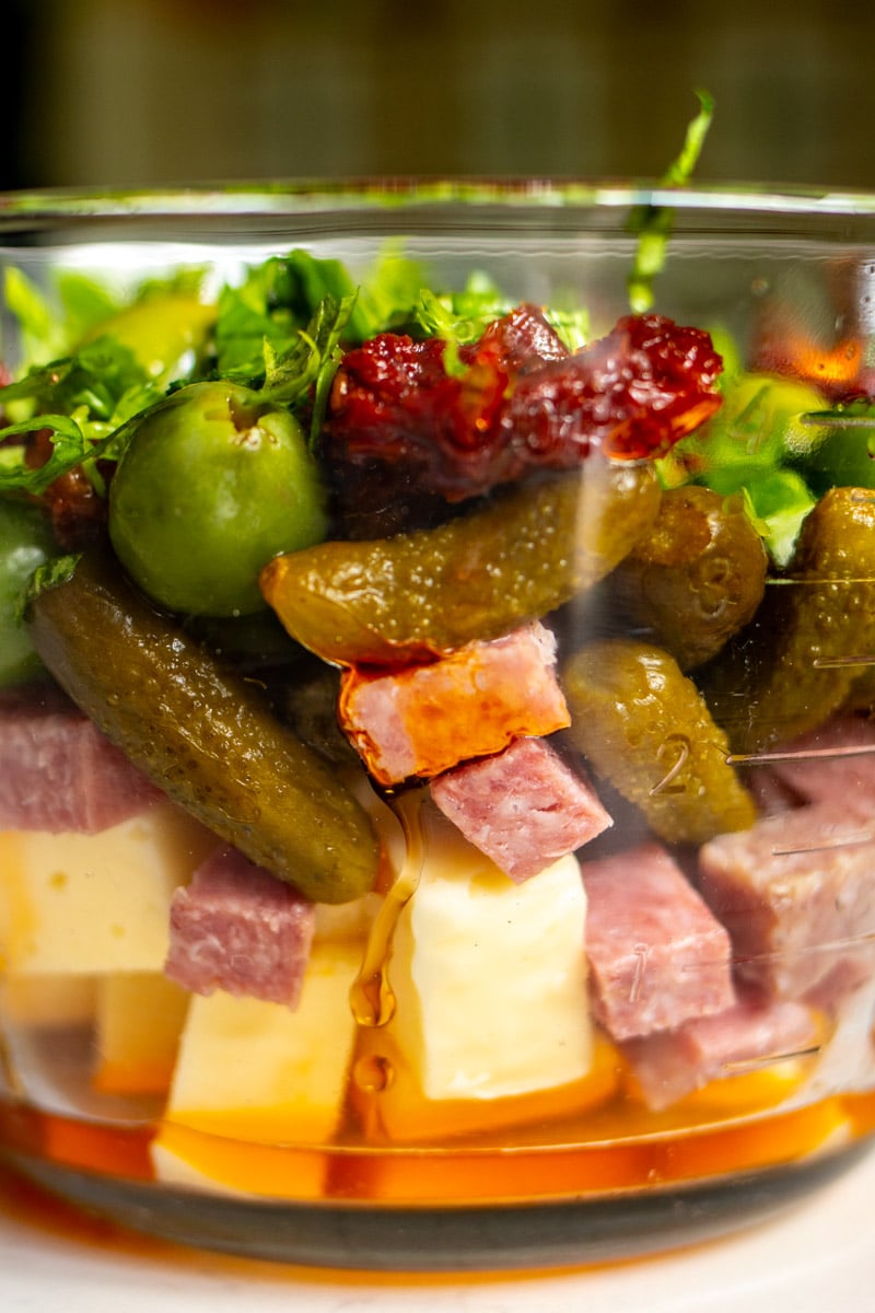 layers of cheese, meat and pickles in a glass jar. 