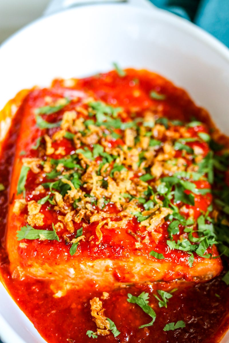 a white baking dish with red spicy salmon in the middle. 