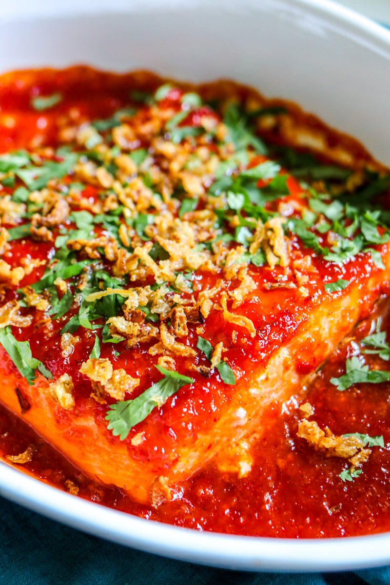 a white baking dish filled with bright red spicy salmon. 