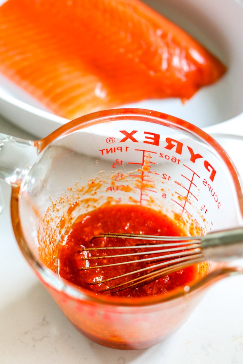 spicy salmon sauce in a clear measuring cup with a whisk. 