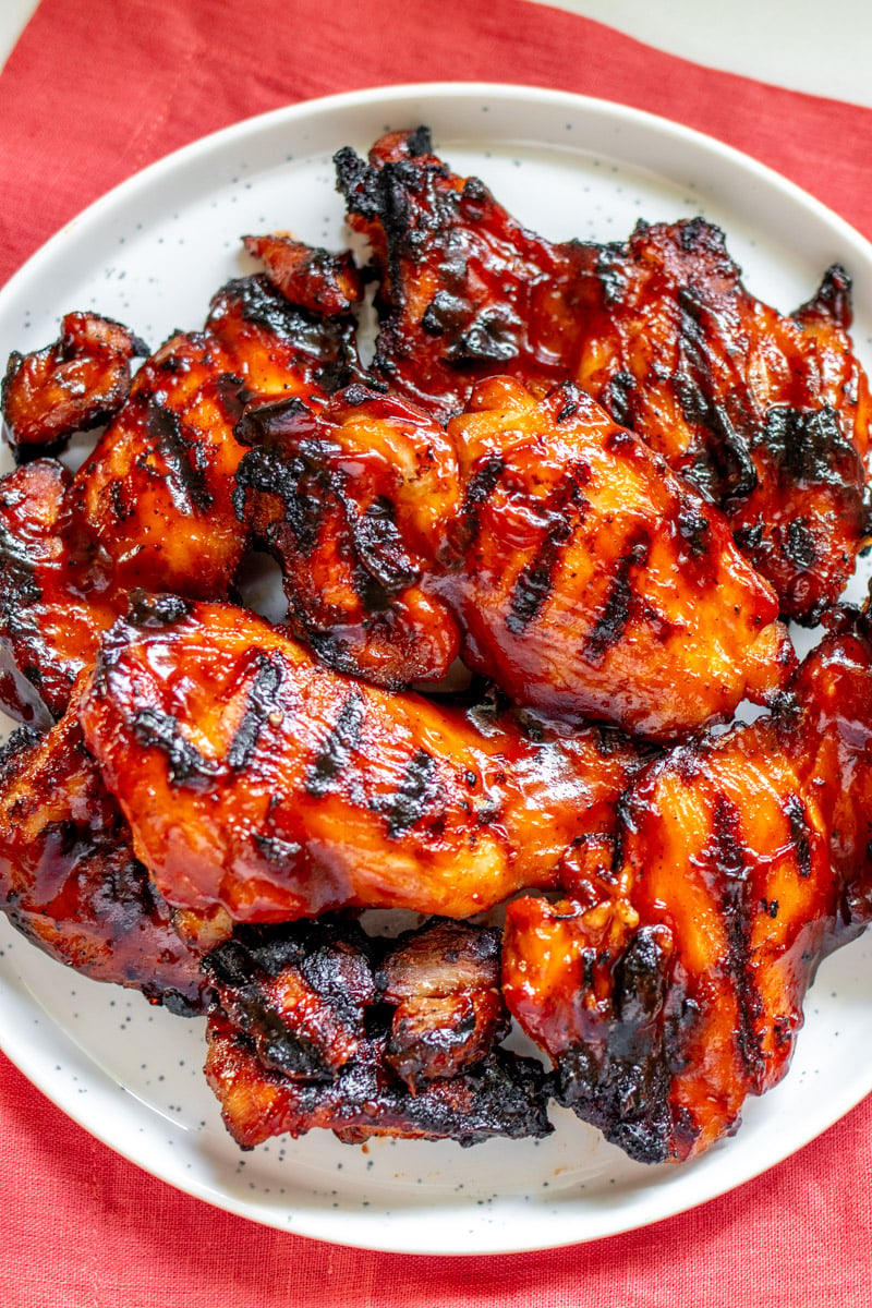a big white plate filled with caramelized bbq chicken thighs. 