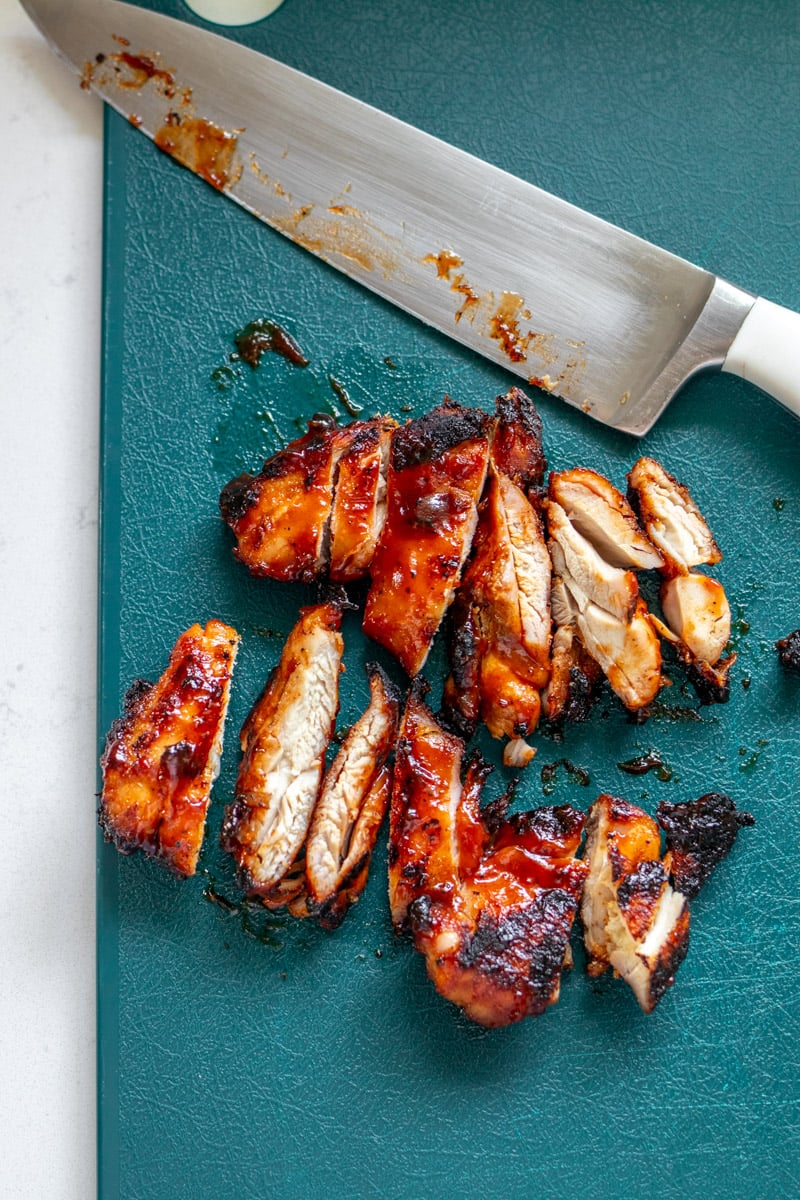 a cutting board with chopped bbq chicken thighs. 
