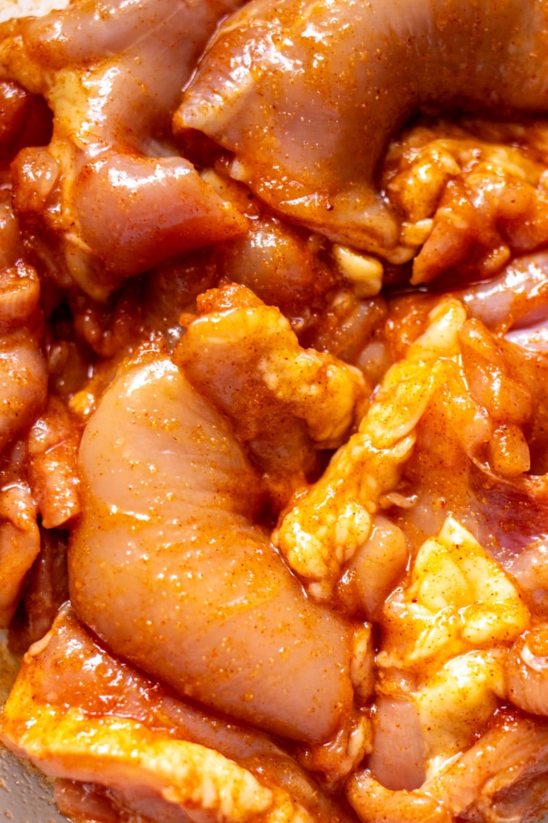 an up close image of marinated chicken thighs with smokey seasoning. 