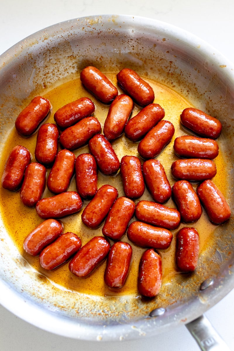 overhead view of cocktail sausages in a silver frying pan.