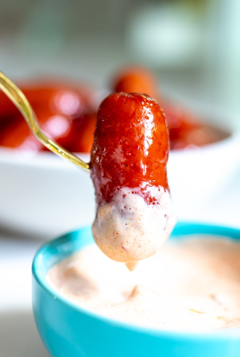 a beer braised cocktail sausage getting dunked into chipotle sauce.