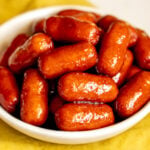 beer braised cocktail sausages in a small white bowl.