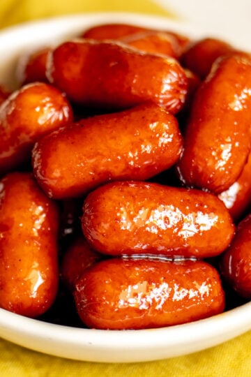 beer braised cocktail sausages in a small white bowl.