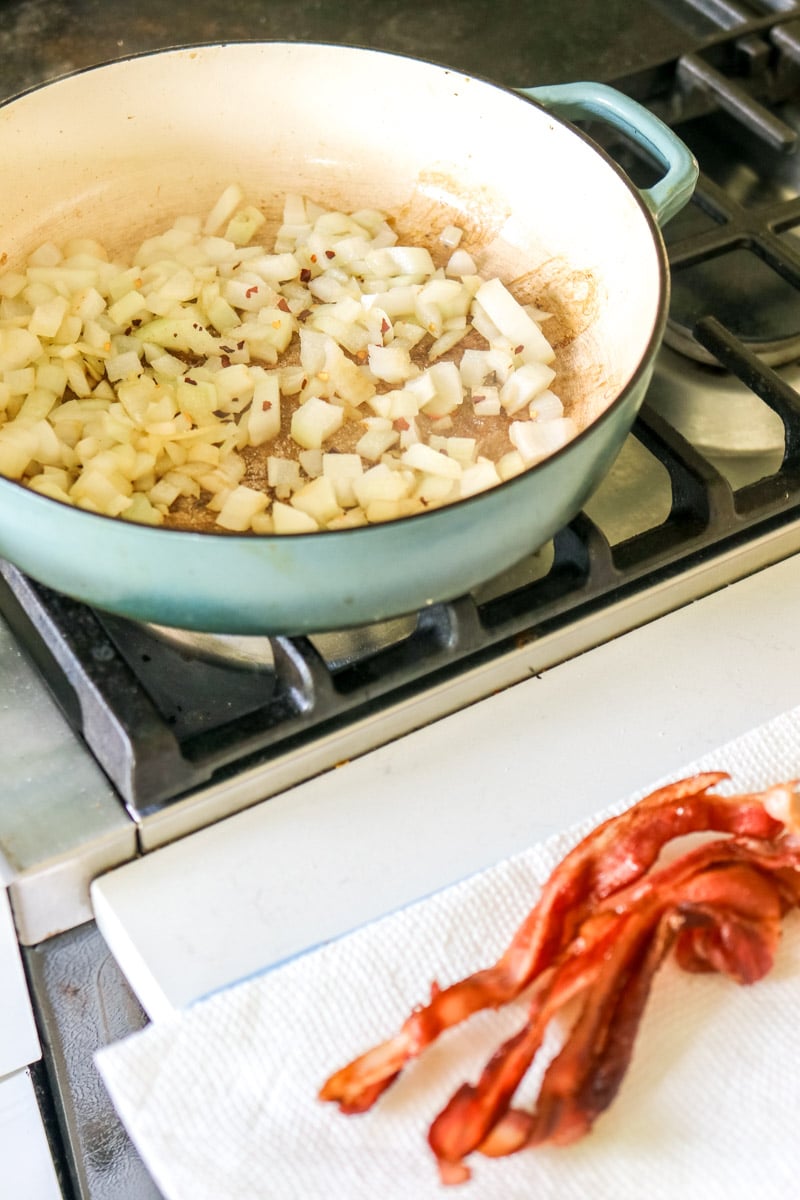 crispy bacon next to a pan full of sauteed onions.