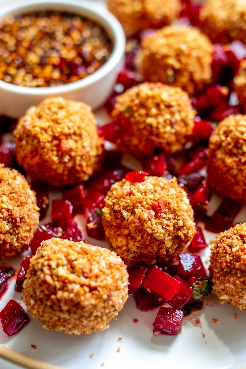 an up close view of some fried goat cheese balls with pickled beets around them.