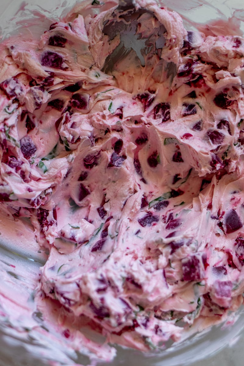 goat cheese mixed up with basil and pickled beets in a glass bowl.