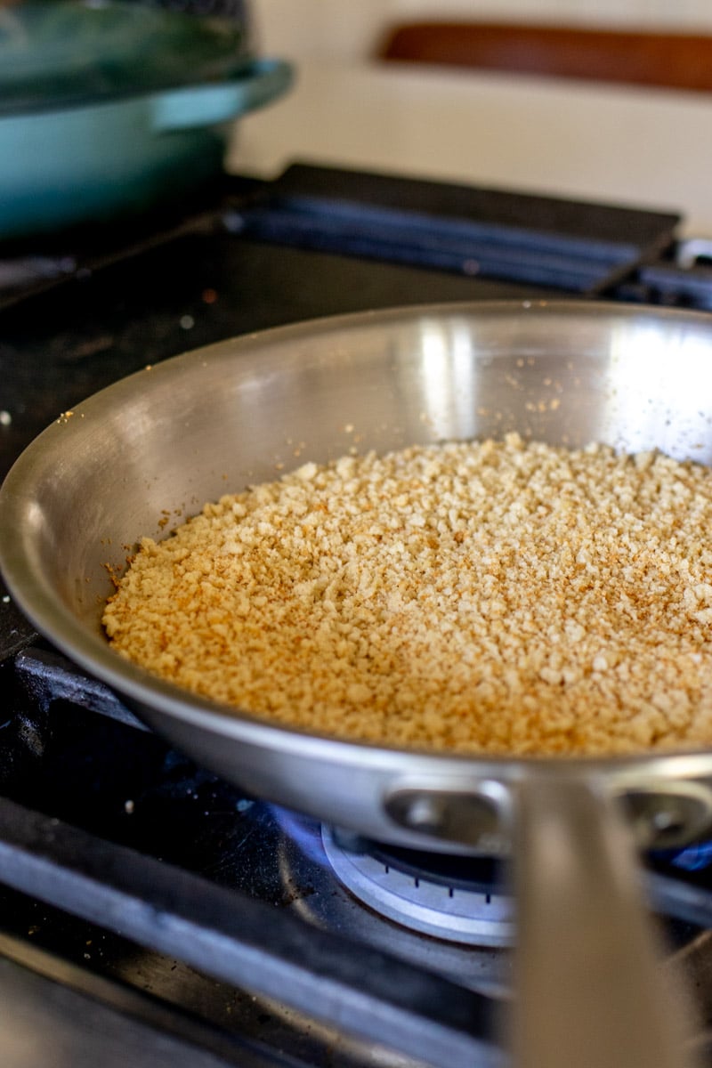 a silver pan with bread crumbs toasting in it.