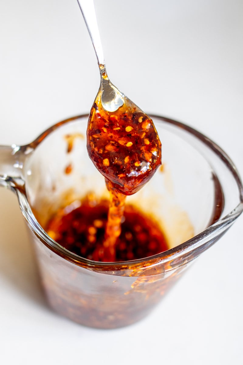 a small measuring cup filled with spicy honey and a spoon.