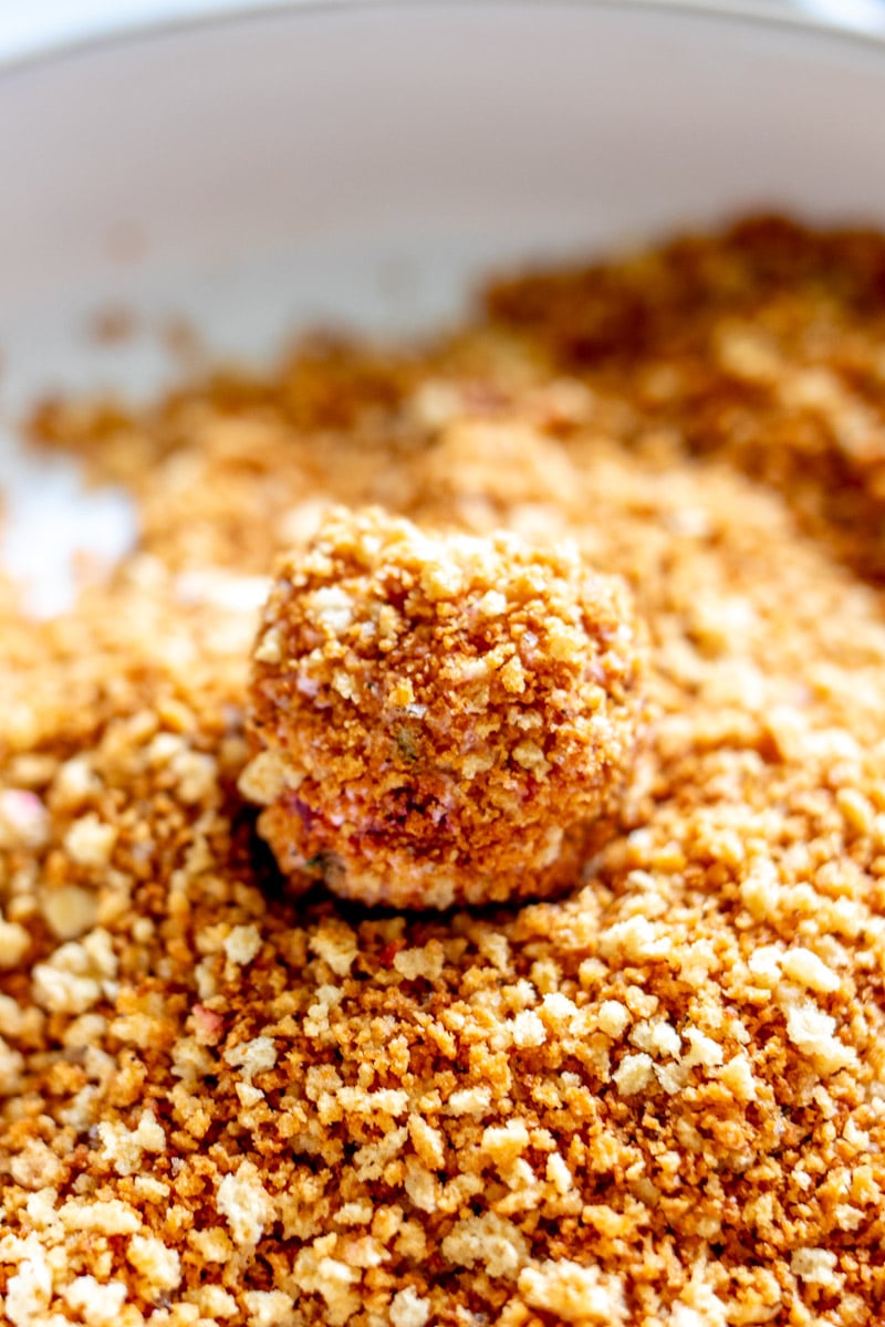 a shallow bowl with toasted bread crumbs with a ball of goat cheese getting its crust.