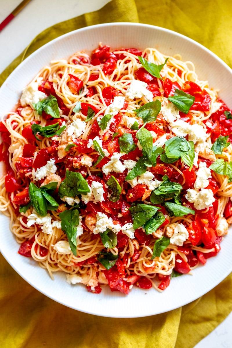 a white plate filled with colorful bruschetta pasta salad