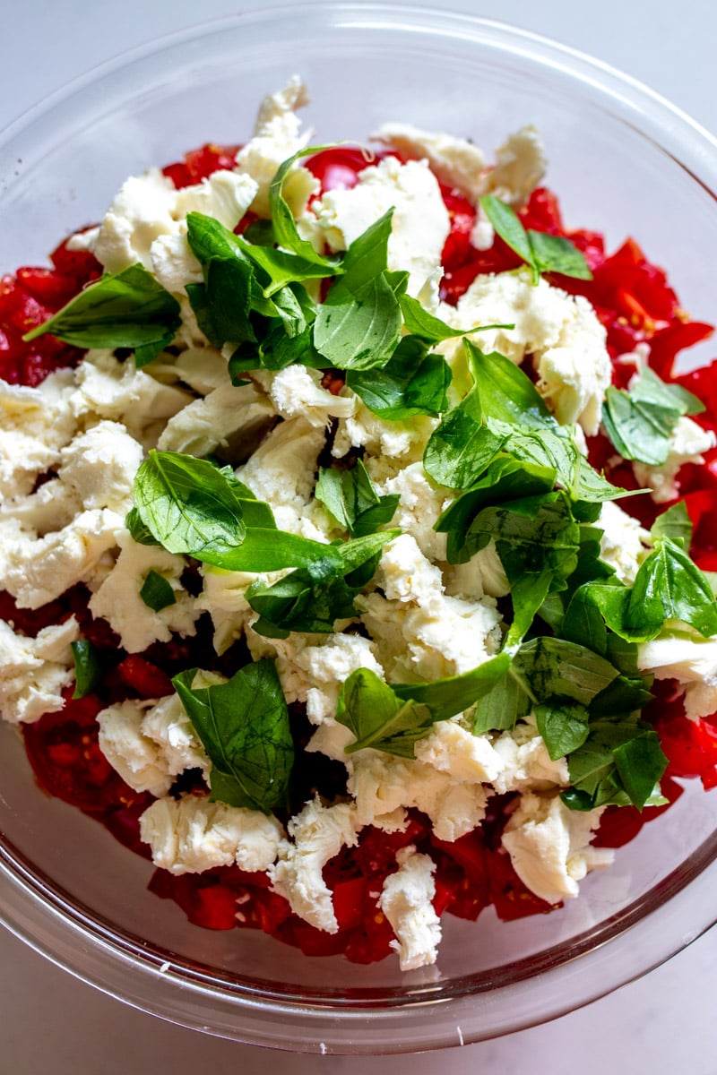 a bowl of torn mozzarella and basil over chopped tomatoes.