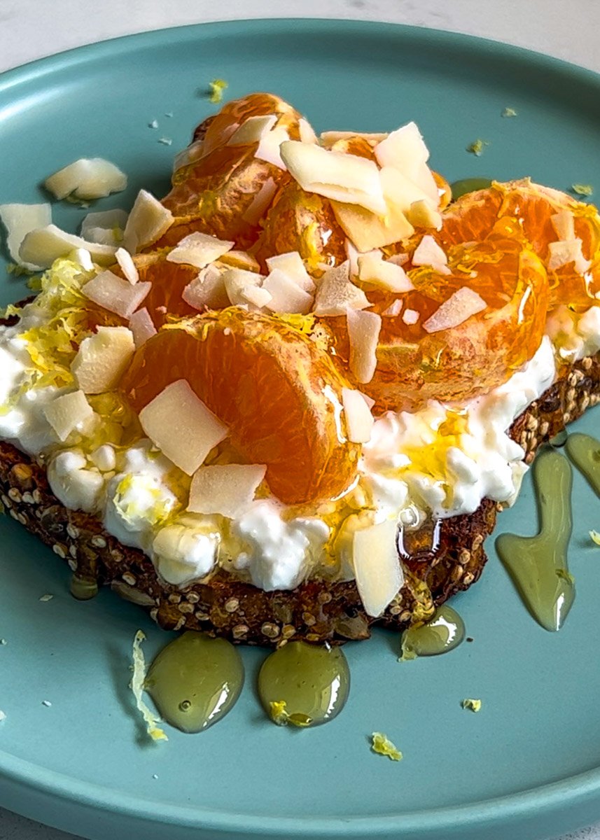 cottage cheese and tangerine toast on a blue plate drizzled with honey.