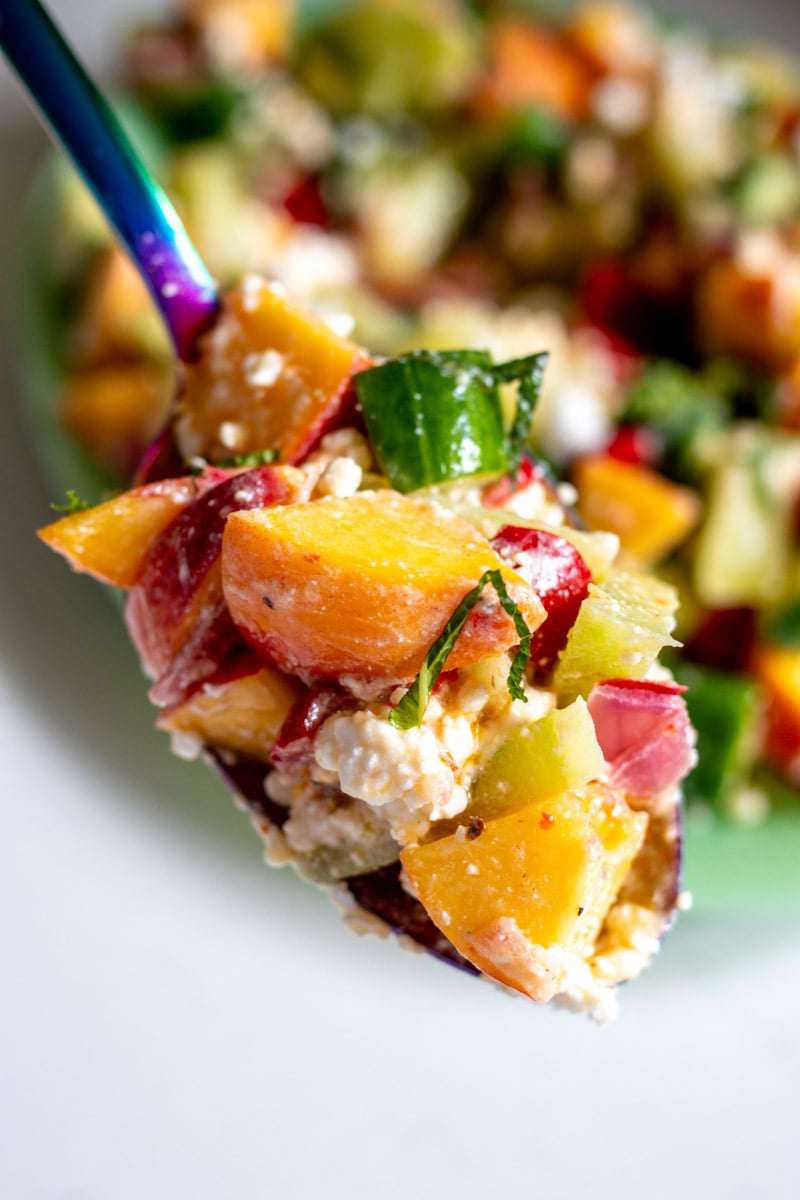 a spoonful of peach cucumber melon salad with feta and mint.